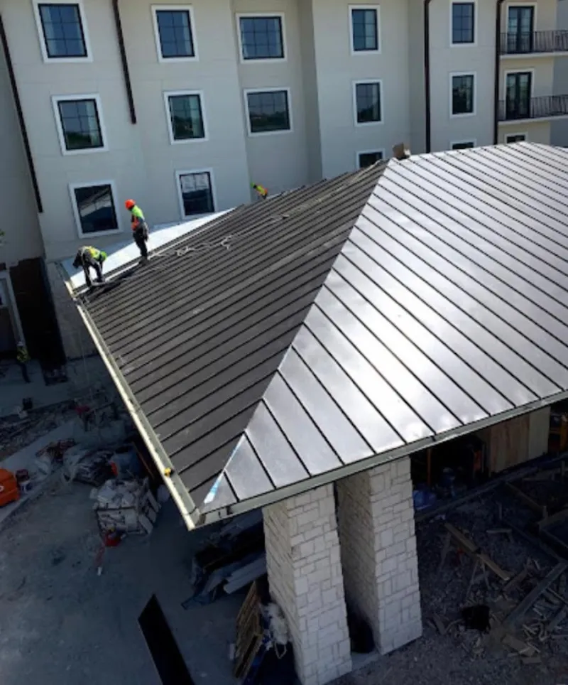 Crew installing standing seam metal roof panels on a commercial project in Butner